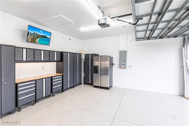 garage with a garage door opener, stainless steel fridge, and electric panel