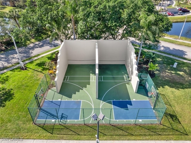 view of basketball court with a water view and a yard