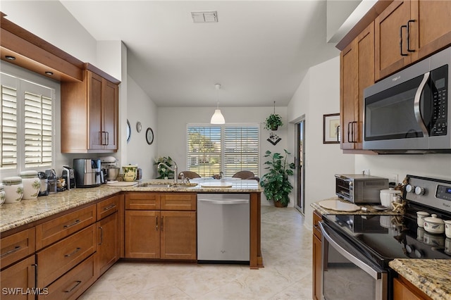 kitchen with appliances with stainless steel finishes, decorative light fixtures, sink, kitchen peninsula, and light stone countertops