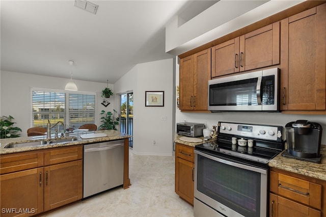 kitchen featuring lofted ceiling, sink, appliances with stainless steel finishes, hanging light fixtures, and light stone counters