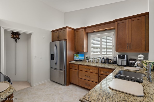 kitchen with light stone counters, stainless steel fridge, and sink