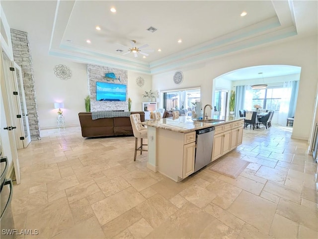 kitchen featuring a raised ceiling, dishwasher, open floor plan, and a center island with sink