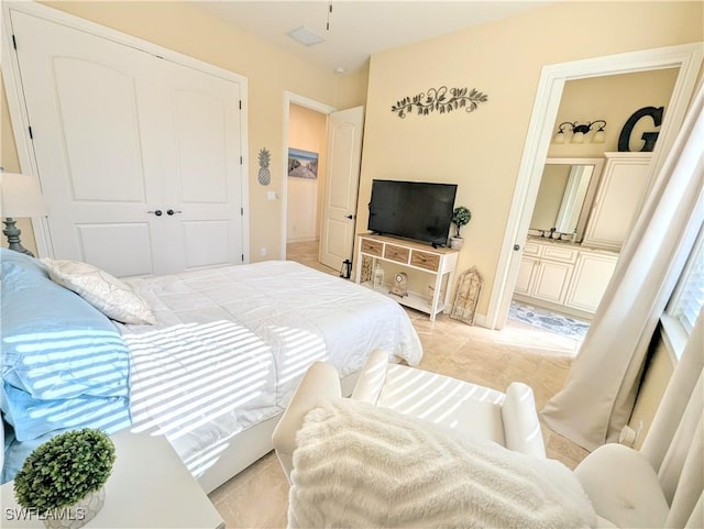 bedroom featuring a closet, ensuite bath, and light tile patterned floors