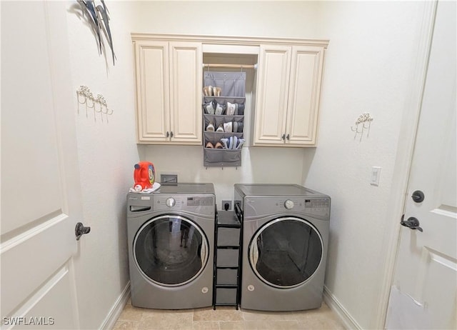 washroom with washing machine and dryer, cabinet space, and baseboards