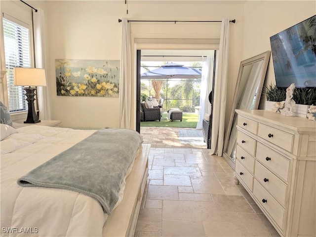 bedroom featuring access to exterior, stone tile flooring, and a sunroom