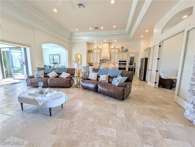 living room featuring arched walkways, a towering ceiling, visible vents, and stone tile floors