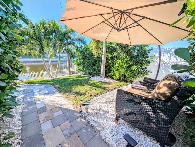 view of patio featuring a water view and fence