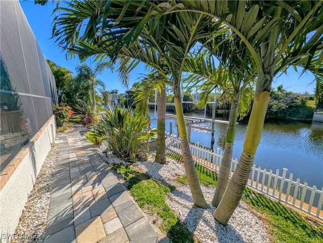 exterior space featuring glass enclosure, a water view, and fence