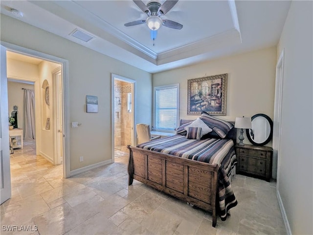 bedroom featuring baseboards, a raised ceiling, connected bathroom, ceiling fan, and stone tile flooring