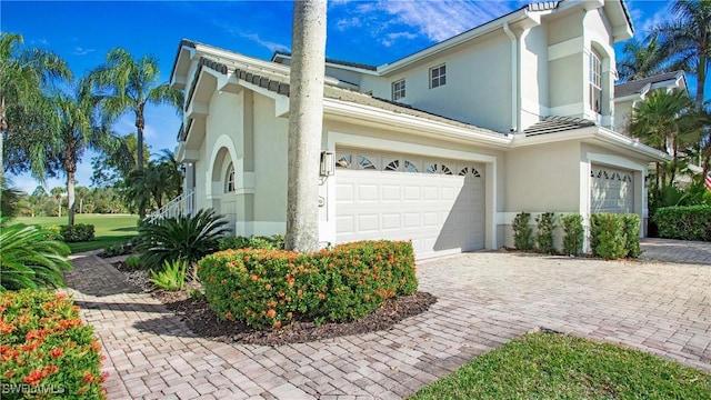 view of home's exterior featuring an attached garage, decorative driveway, and stucco siding