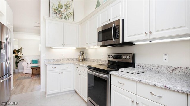 kitchen with white cabinetry, stainless steel appliances, and light stone counters