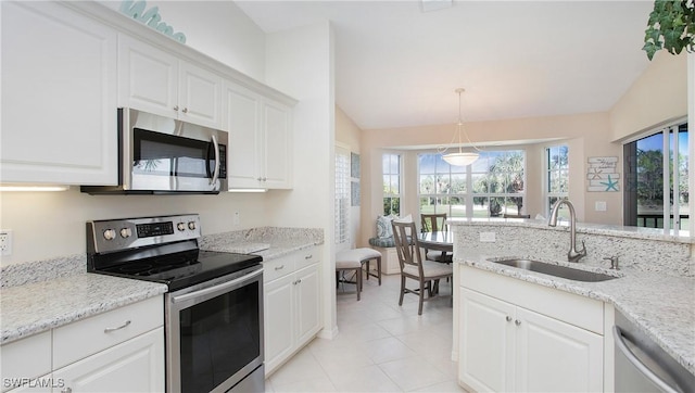 kitchen with vaulted ceiling, appliances with stainless steel finishes, pendant lighting, white cabinetry, and sink