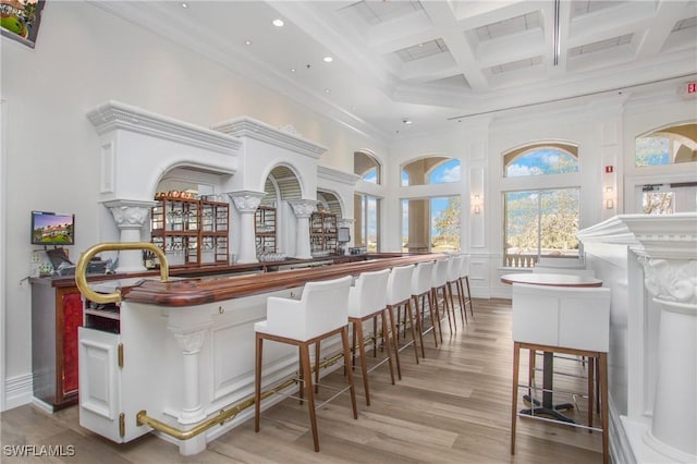 bar with a towering ceiling, butcher block countertops, beamed ceiling, white cabinetry, and coffered ceiling