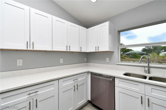 kitchen featuring lofted ceiling, sink, white cabinetry, light stone countertops, and stainless steel dishwasher