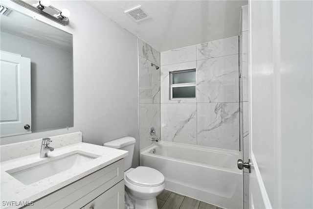 full bathroom featuring vanity, tiled shower / bath combo, and toilet