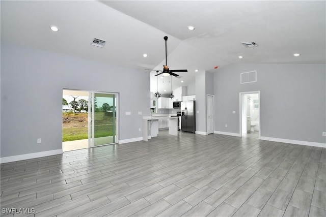 unfurnished living room with ceiling fan and high vaulted ceiling