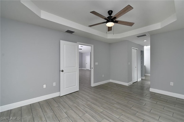 unfurnished room featuring a raised ceiling and ceiling fan