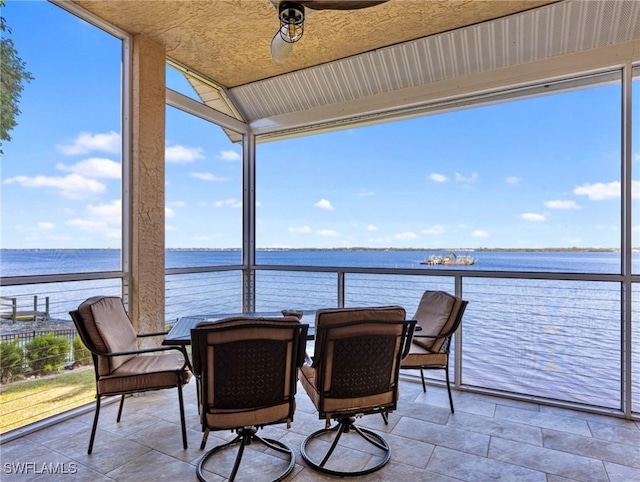 sunroom / solarium with lofted ceiling, ceiling fan, and a water view