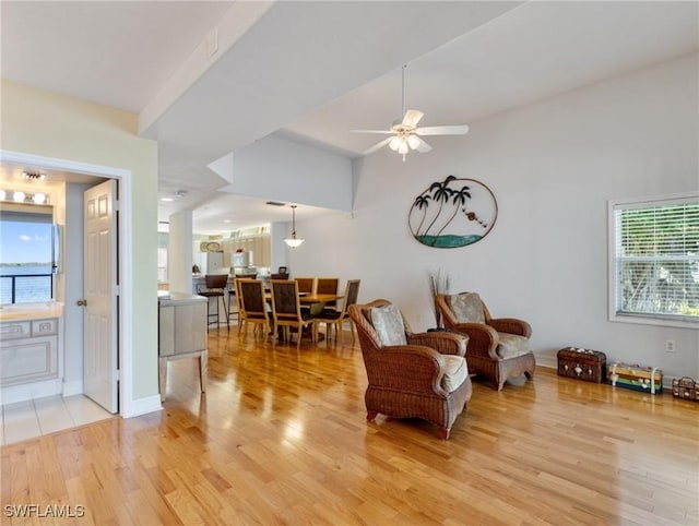 living area with light hardwood / wood-style flooring, ceiling fan, and vaulted ceiling