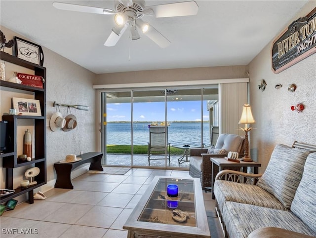 tiled living room featuring a water view and ceiling fan