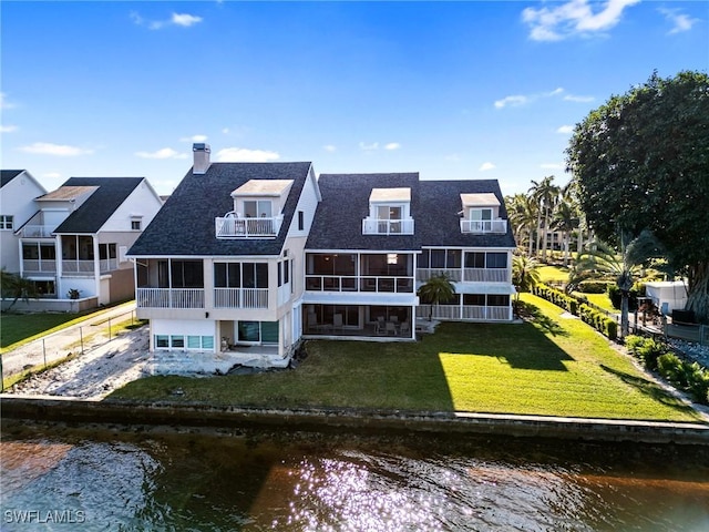 rear view of property with a water view and a lawn