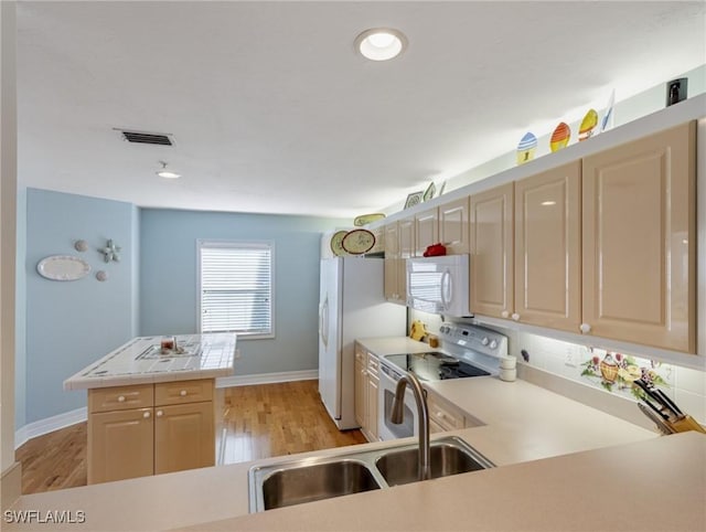 kitchen with sink, white appliances, light hardwood / wood-style floors, kitchen peninsula, and light brown cabinets