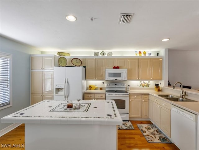 kitchen featuring a center island, sink, white appliances, and light hardwood / wood-style floors