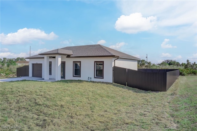 back of property featuring a garage and a yard