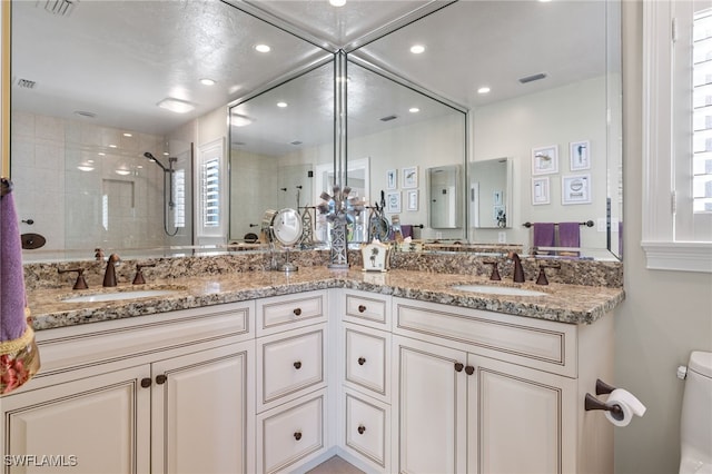 bathroom featuring vanity, toilet, and a tile shower