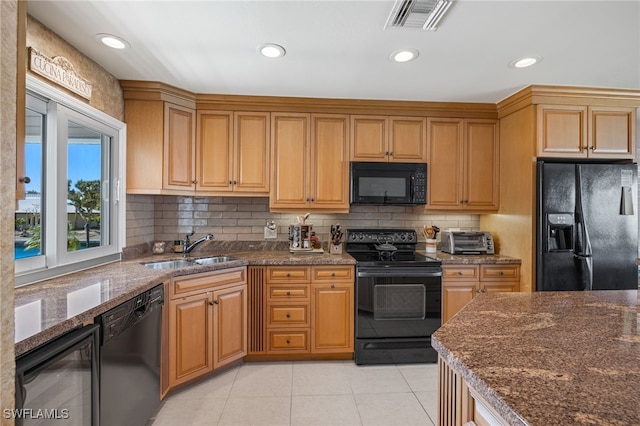 kitchen featuring sink, dark stone countertops, backsplash, light tile patterned floors, and black appliances