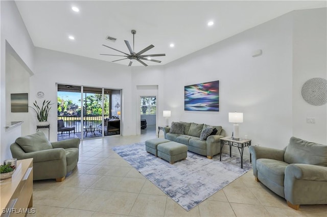 tiled living room with ceiling fan and a towering ceiling