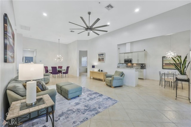 living room featuring a towering ceiling and ceiling fan with notable chandelier