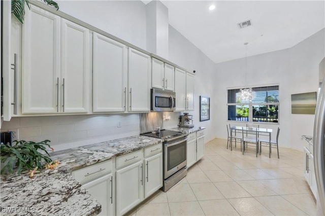 kitchen with light stone counters, light tile patterned floors, decorative backsplash, and appliances with stainless steel finishes