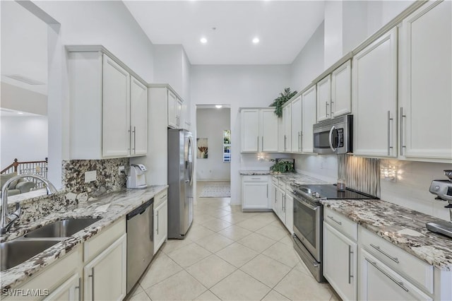 kitchen featuring sink, light tile patterned floors, light stone countertops, and appliances with stainless steel finishes