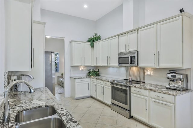 kitchen with stainless steel appliances, sink, and light stone counters