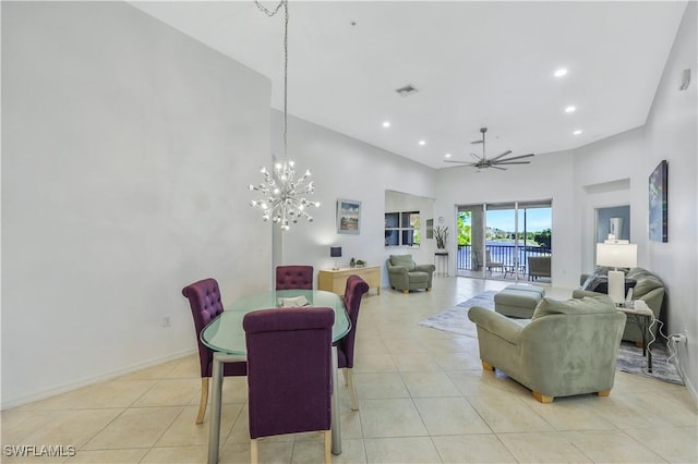 dining room featuring light tile patterned floors, ceiling fan with notable chandelier, and a high ceiling