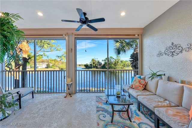 sunroom with ceiling fan and a water view