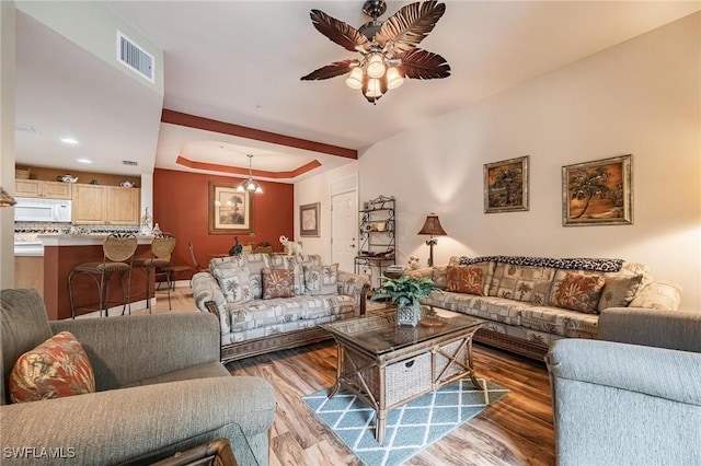 living room featuring ceiling fan with notable chandelier, light wood-type flooring, and visible vents