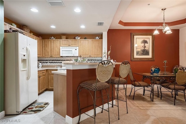 kitchen featuring light countertops, white appliances, a kitchen bar, and visible vents