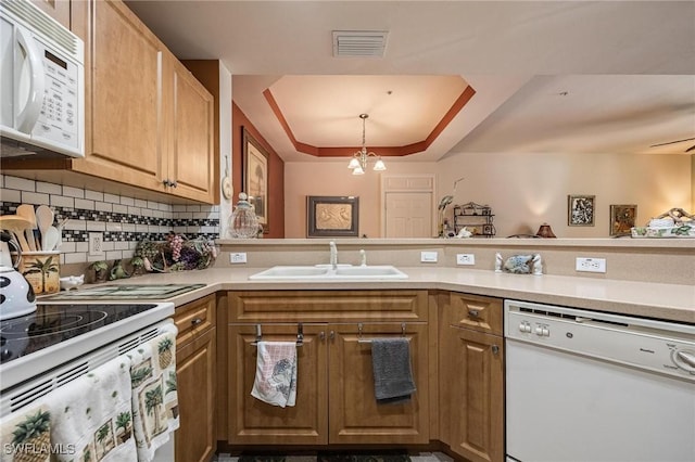 kitchen with a chandelier, white appliances, a sink, visible vents, and backsplash