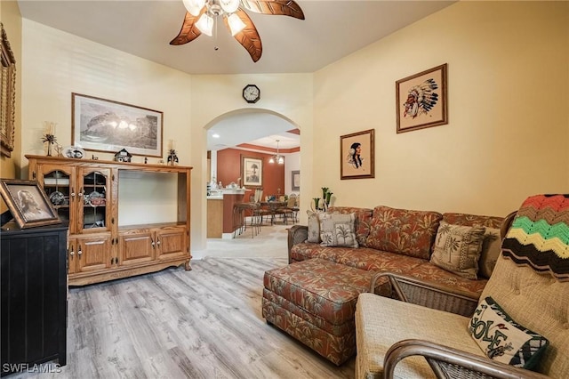 living area featuring a ceiling fan, arched walkways, and light wood-style floors