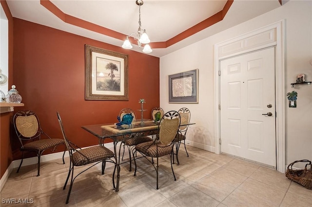 dining room featuring a chandelier, a raised ceiling, light tile patterned flooring, and baseboards