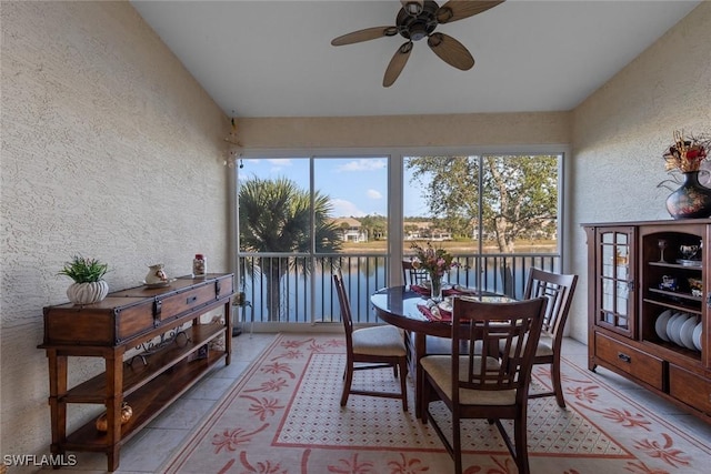 sunroom / solarium featuring a water view and ceiling fan