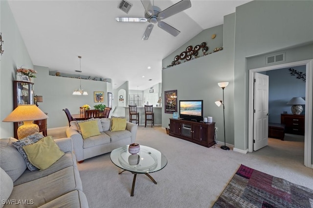 carpeted living room featuring ceiling fan with notable chandelier and high vaulted ceiling