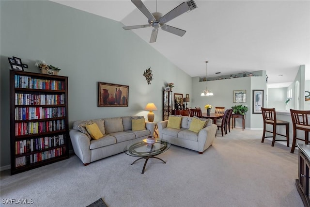 carpeted living room with ceiling fan with notable chandelier and high vaulted ceiling