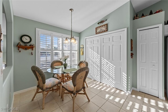 dining space with an inviting chandelier, light tile patterned floors, and vaulted ceiling