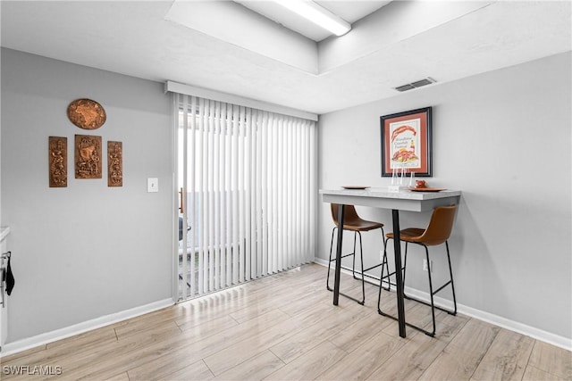 dining room with a tray ceiling and light hardwood / wood-style flooring