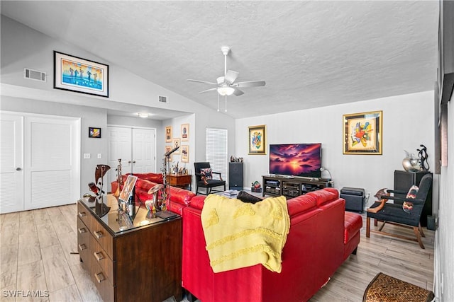 living room featuring ceiling fan, lofted ceiling, a textured ceiling, and light hardwood / wood-style floors