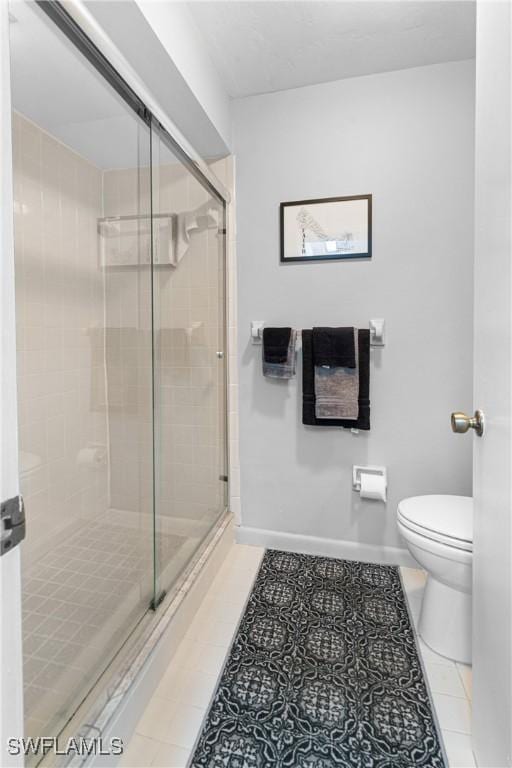 bathroom featuring tile patterned floors, toilet, and a shower with door