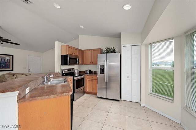 kitchen featuring lofted ceiling, sink, light tile patterned floors, stainless steel appliances, and kitchen peninsula